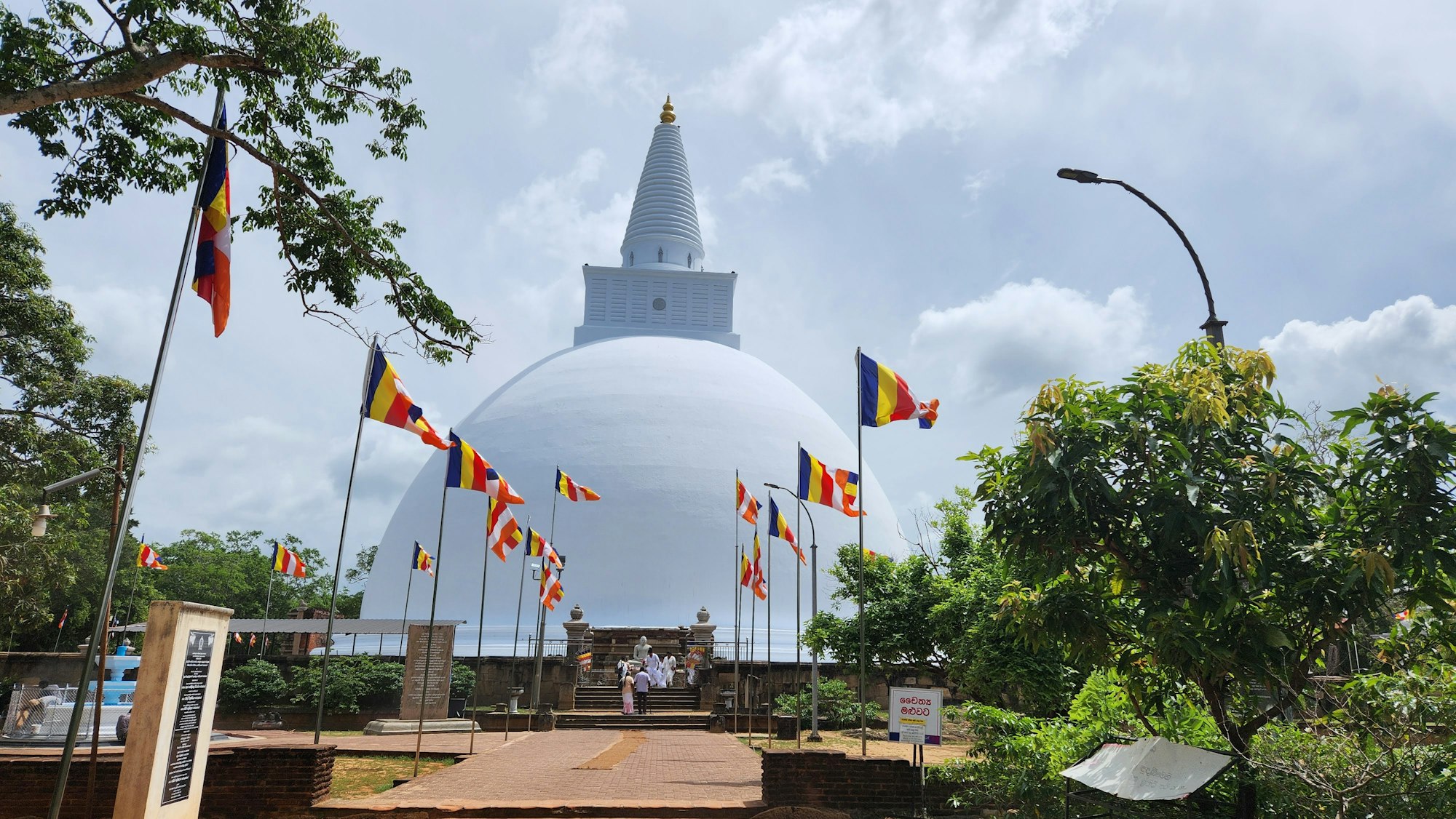 A white dagoba hung with rows of Buddhist prayer flags